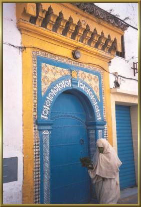 Verhüllte Frau vor einem der prächtigen Hauseingänge in Essaouira